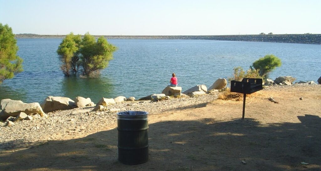 Individual sitting on a rock at the bank of Folsom Lake recreation area.