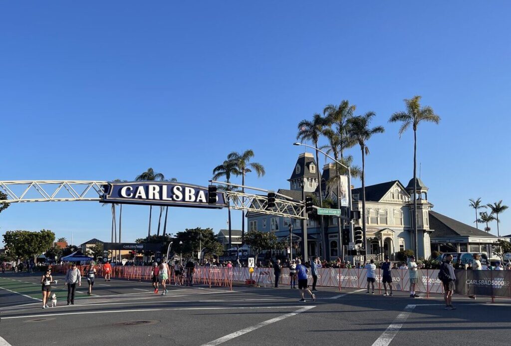 Downtown Carlsbad CA sign arching over a busy street crossing, welcoming visitors to the heart of the city. 